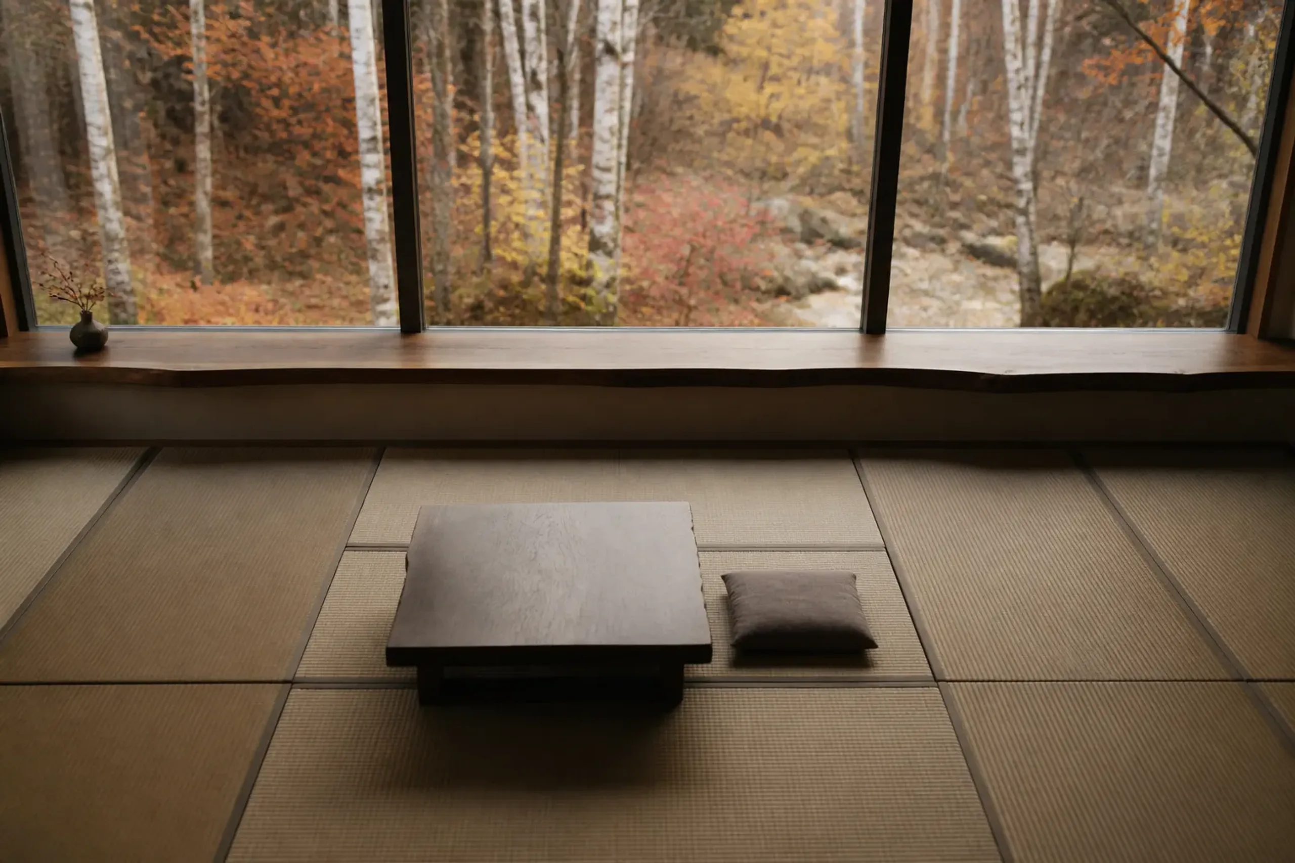 A quiet tatami room in a luxury ryokan looking out at yellow birch trees in Hokkaido.