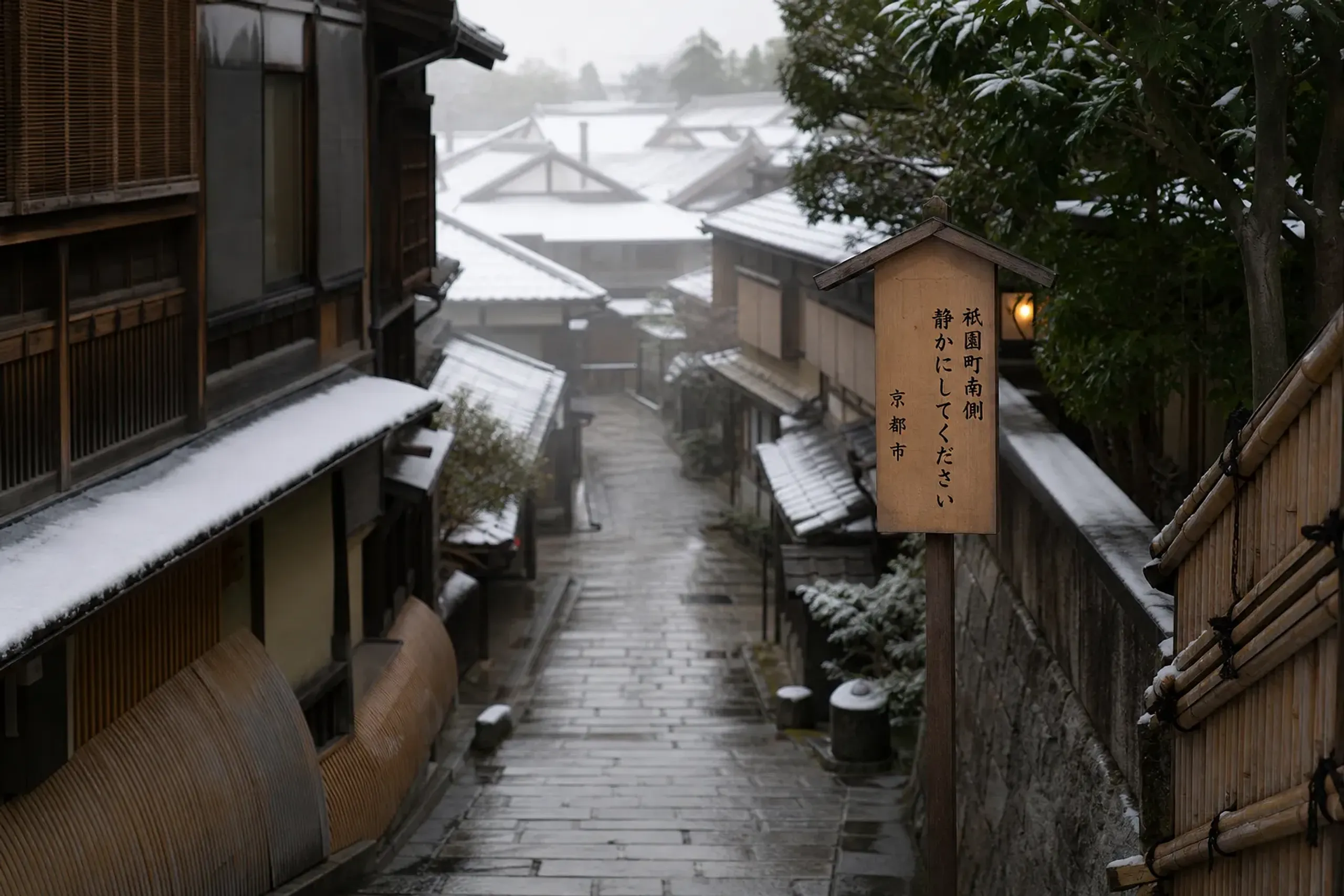 Cobbled residential street in Southern Gion Kyoto with traditional townhouses and a quiet-area signboard