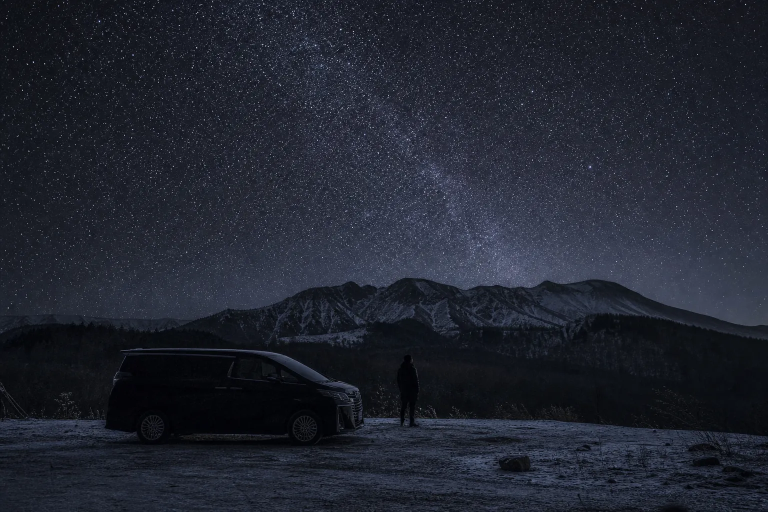 Private vehicle waiting at a dark roadside viewpoint while a traveler looks up at the stars in Hokkaido