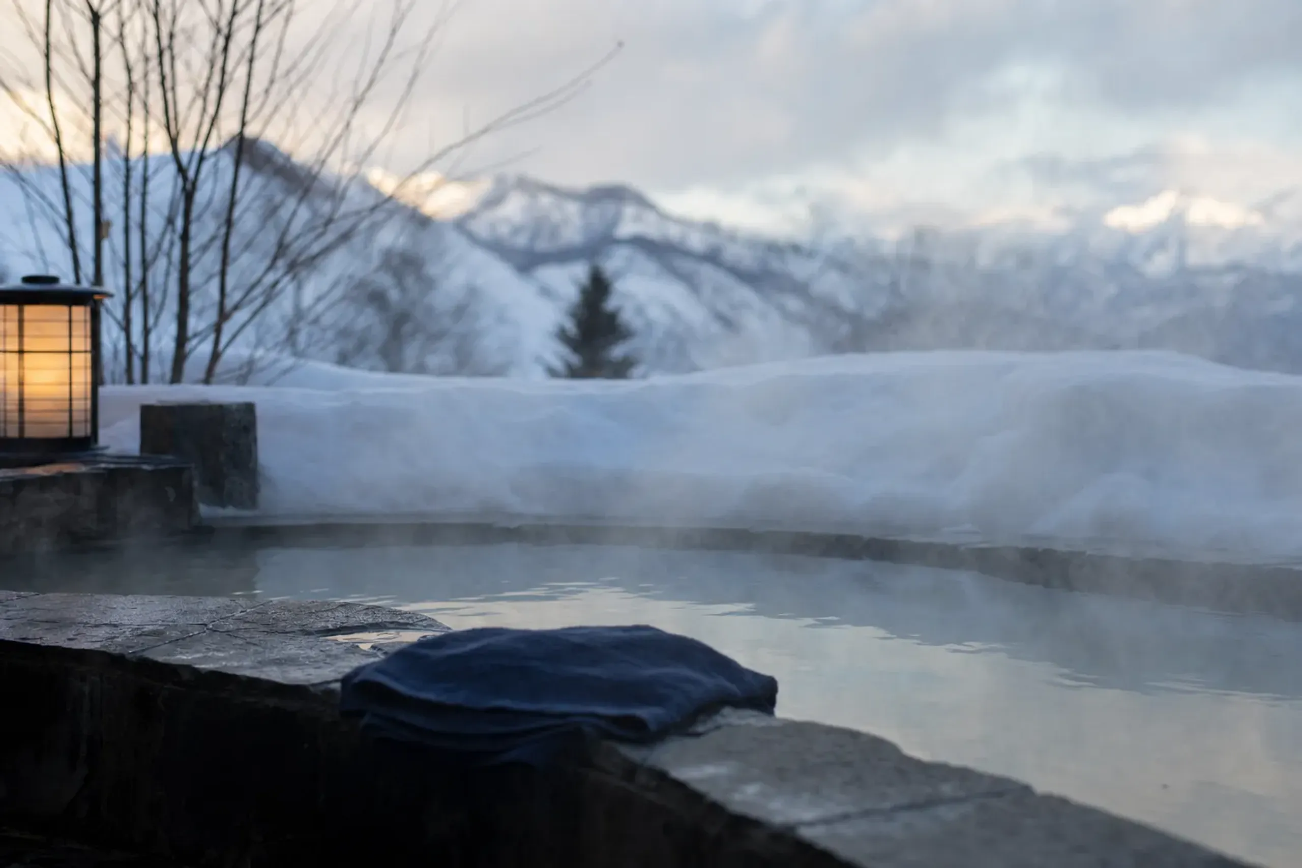 Steaming outdoor onsen bath surrounded by deep snow in rural Hokkaido