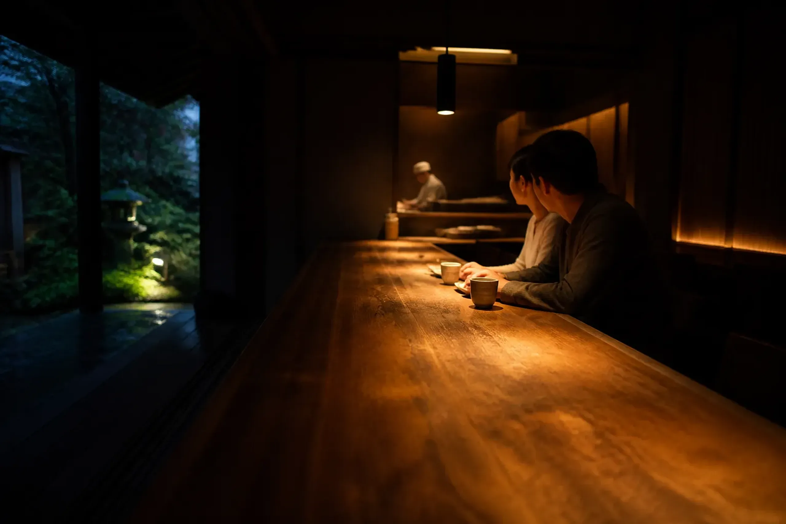 Guests dining quietly at a wooden counter in a understated Japanese restaurant