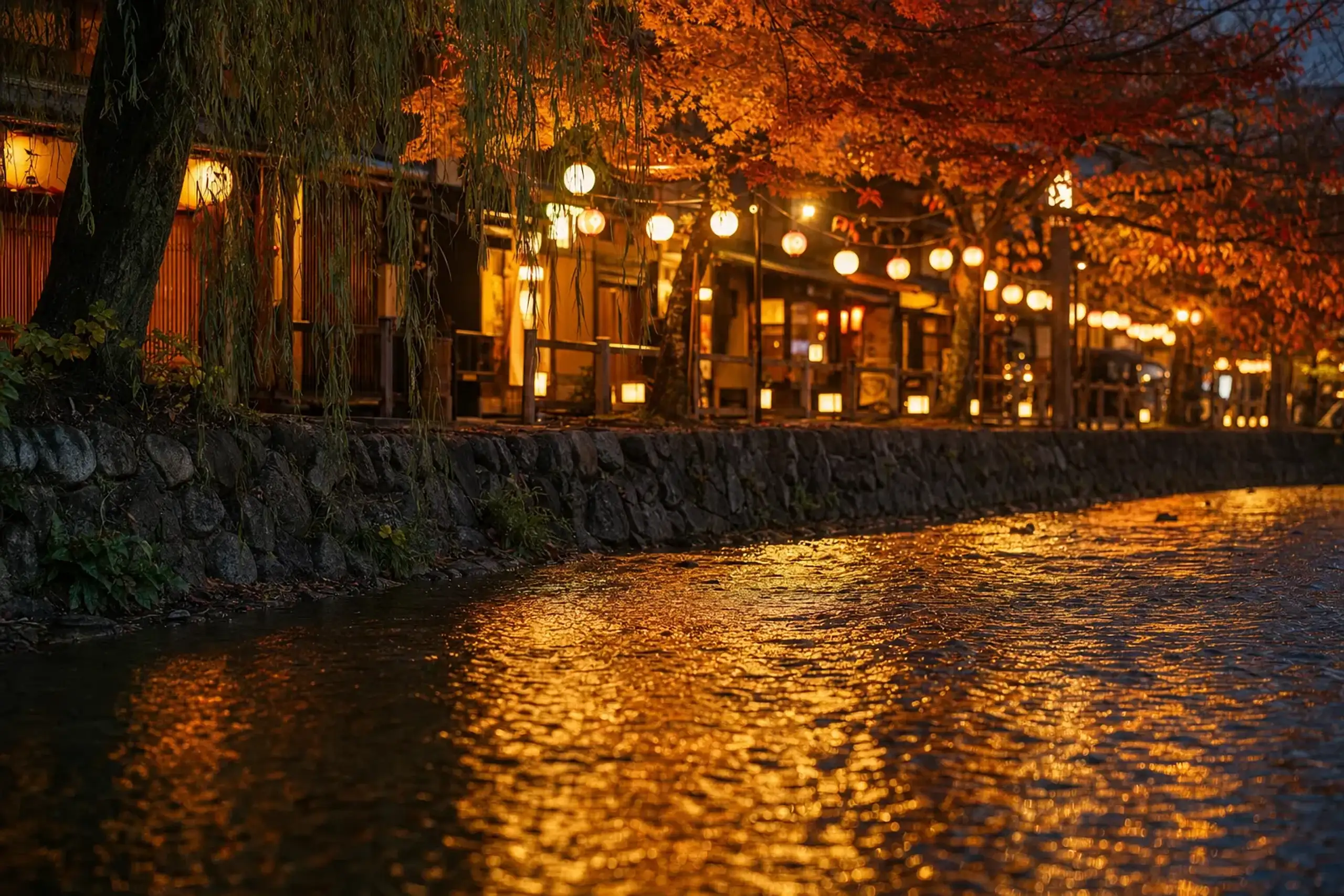 The Shirakawa River running past Shinmonzen Street in Gion, with stone-lined banks and lantern-lit lanes at early evening