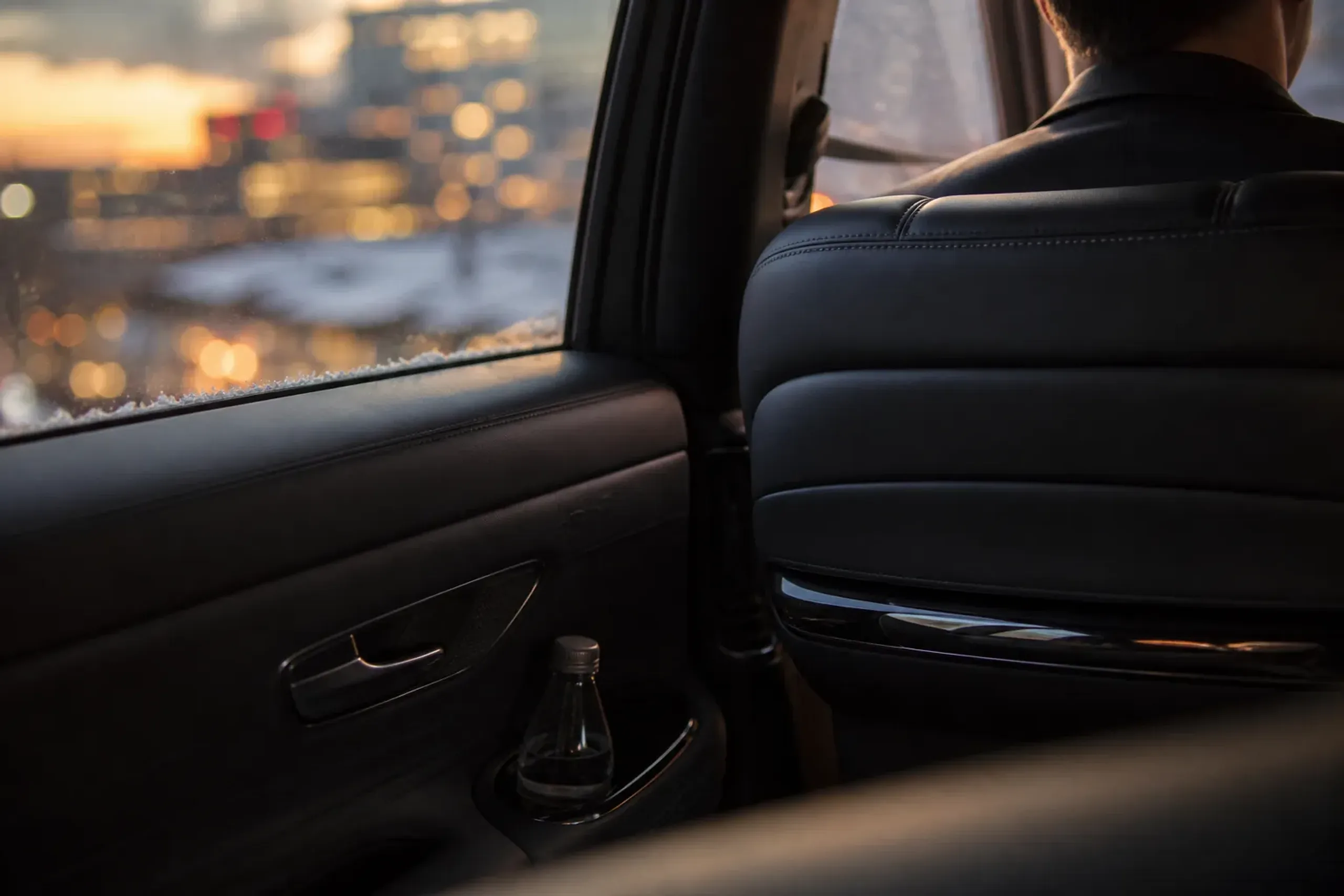 Quiet luxury car interior at dusk with soft city lights outside the window