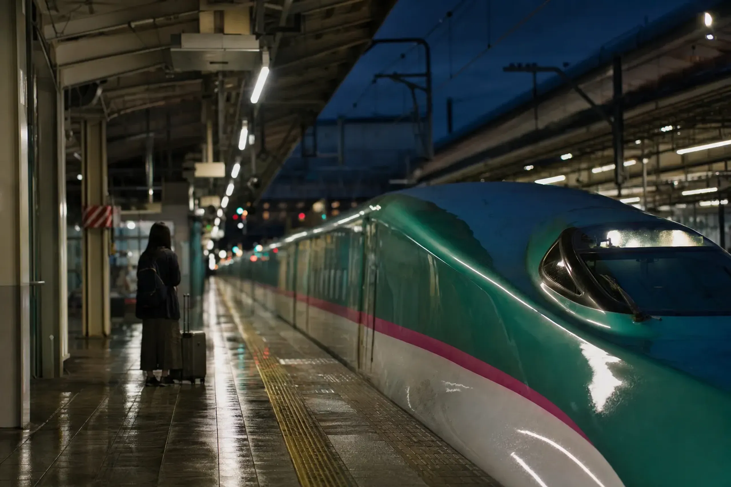 A Tohoku shinkansen train pulling into an illuminated platform at Aomori Station at night during early August