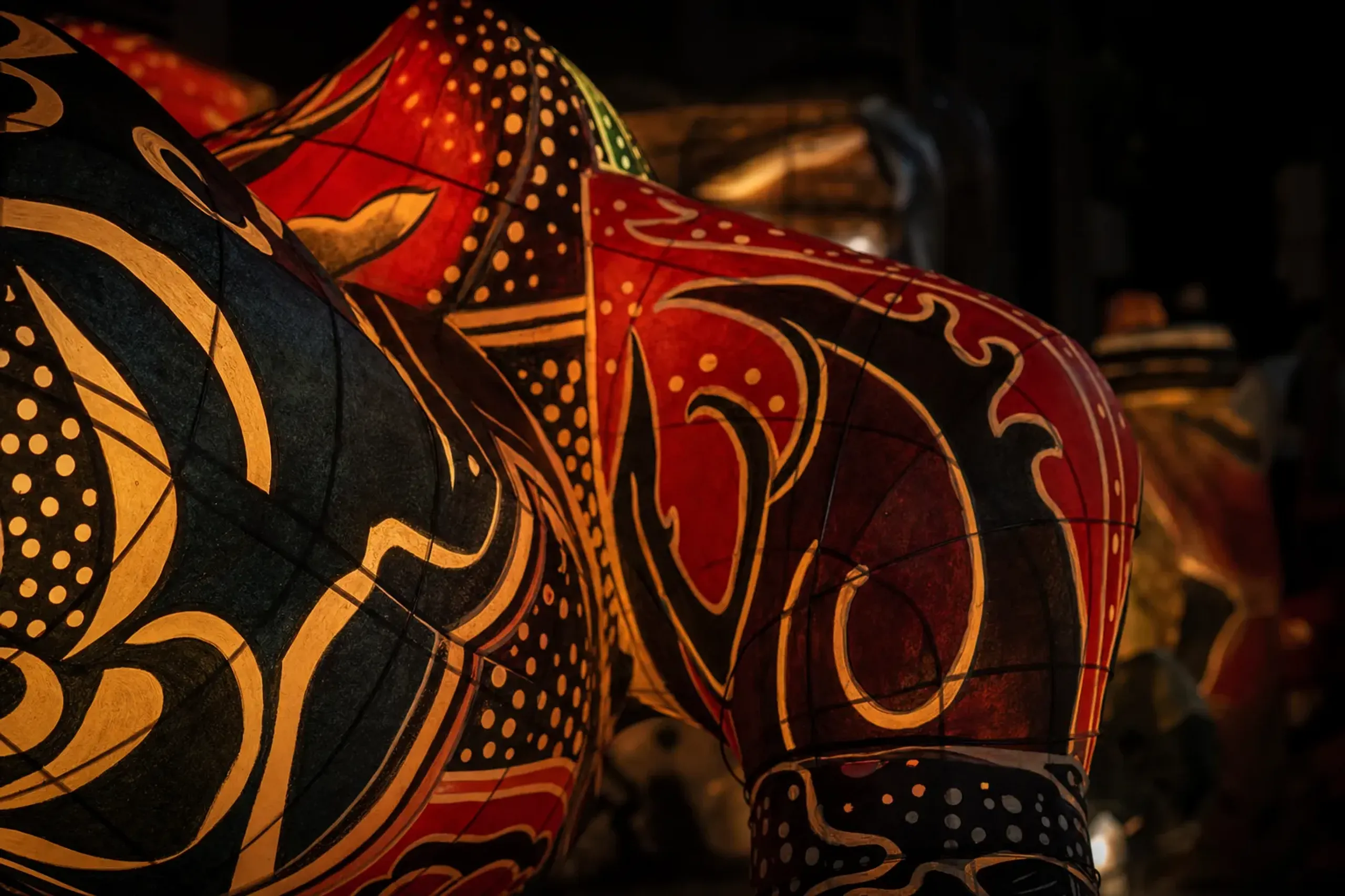 A close-up of a giant Nebuta float's wire ribs reading through glowing painted washi paper at the parade edge