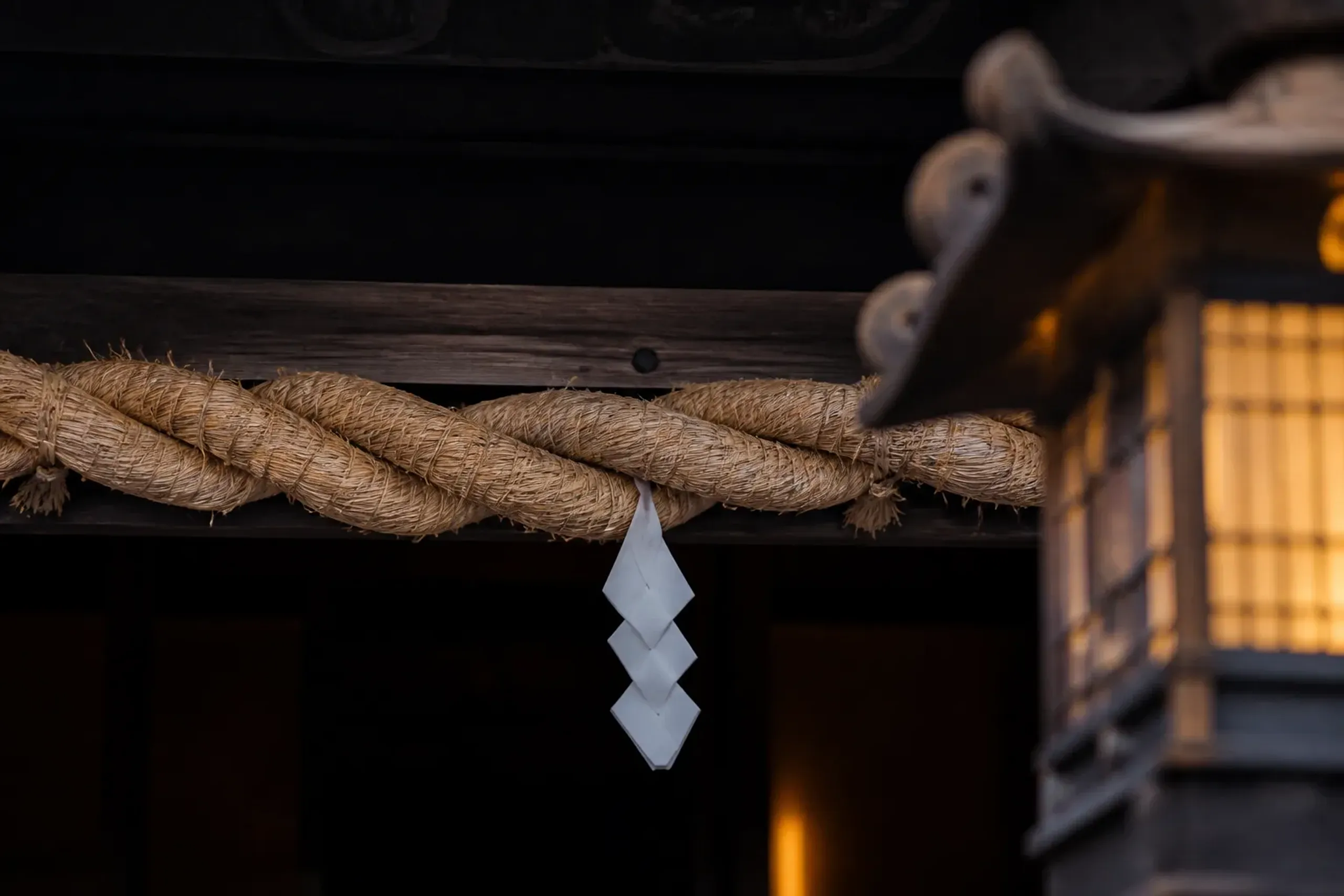 Shimenawa rope with shide streamers marking a sacred boundary at a Japanese temple