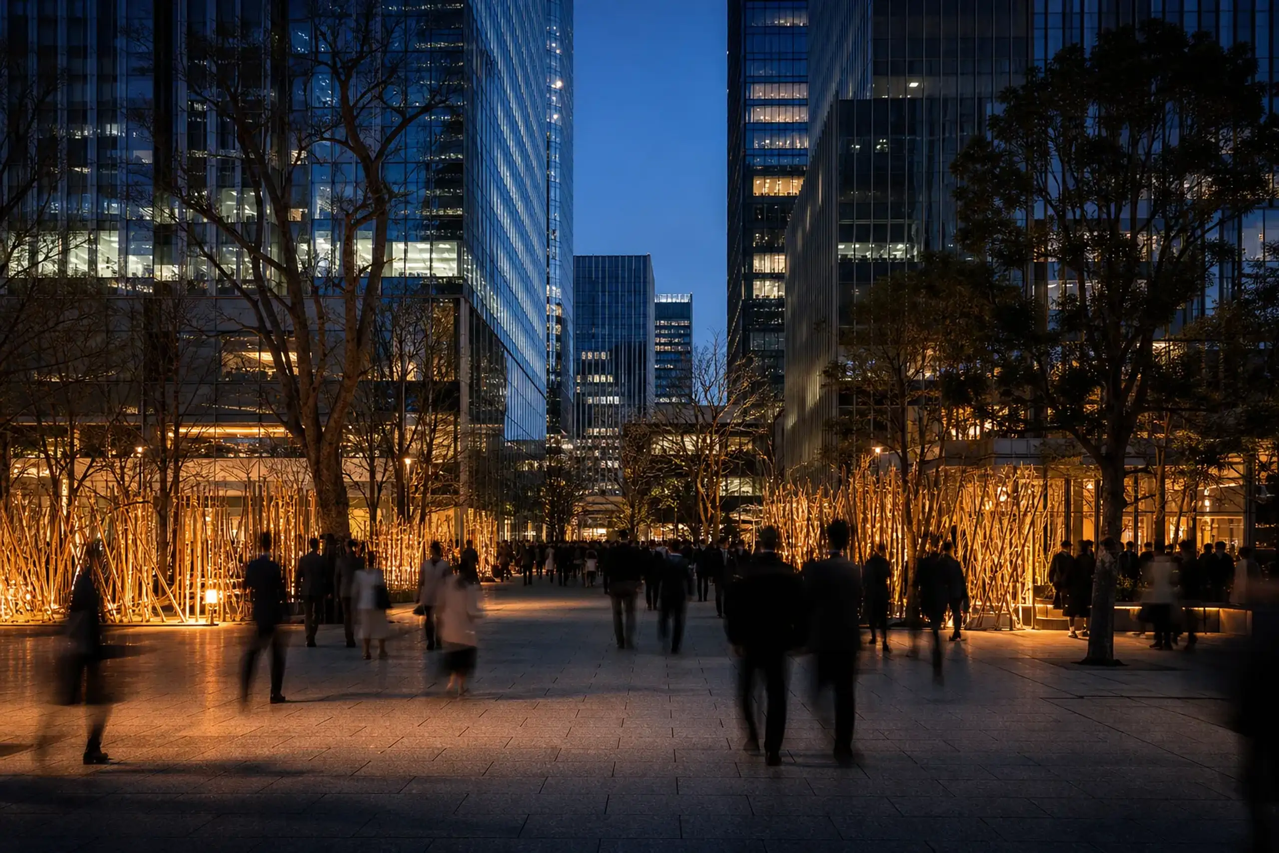 Modern buildings and a public plaza in Hibiya–Marunouchi with art lighting and people walking at dusk
