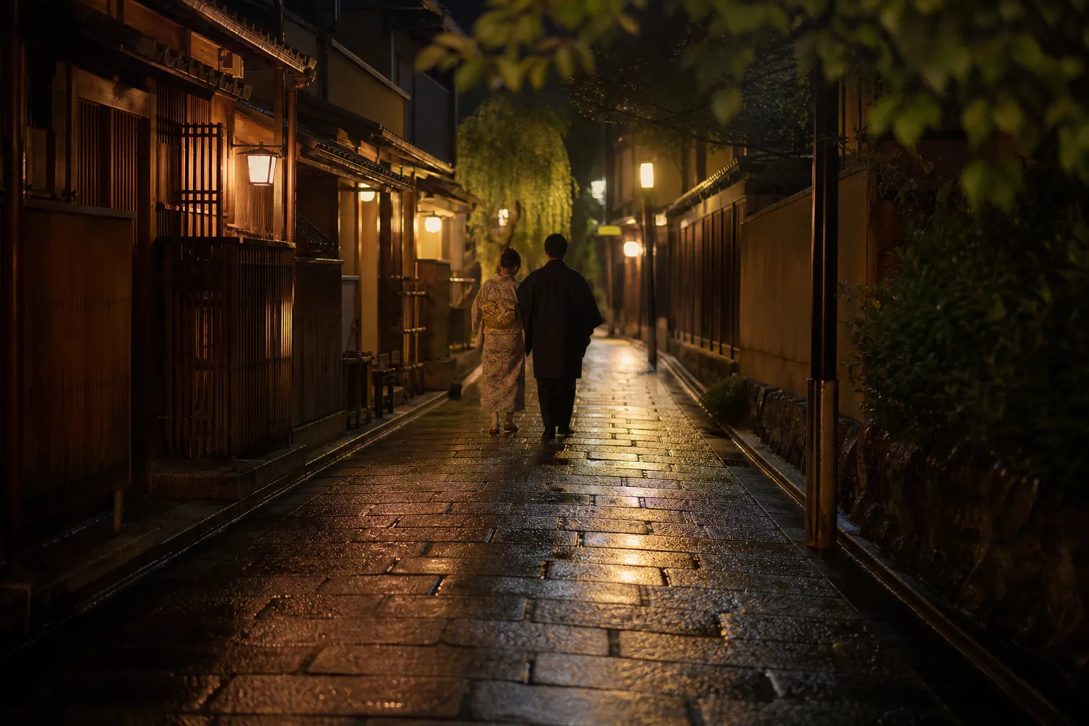 Lantern-lit street in Kyoto Gion at night with a couple walking on stone pavement