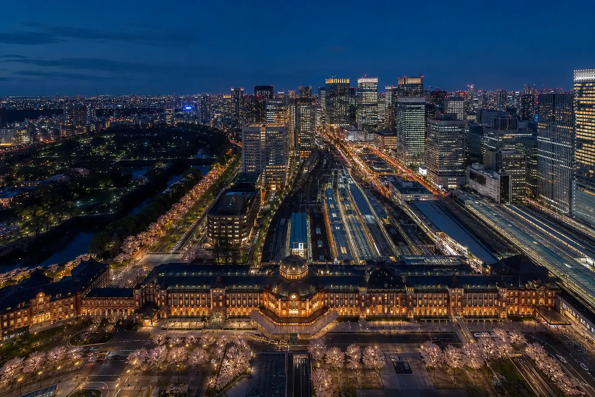 Aerial view of central Tokyo showing Marunouchi towers, Tokyo Station, and the Imperial Palace grounds at dusk