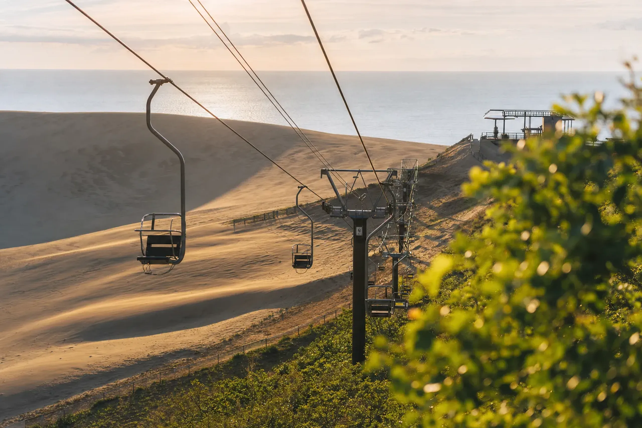 The Sakyu Center chairlift ascending toward the observation deck above the Tottori Sand Dunes, with the Sea of Japan visible in the distance