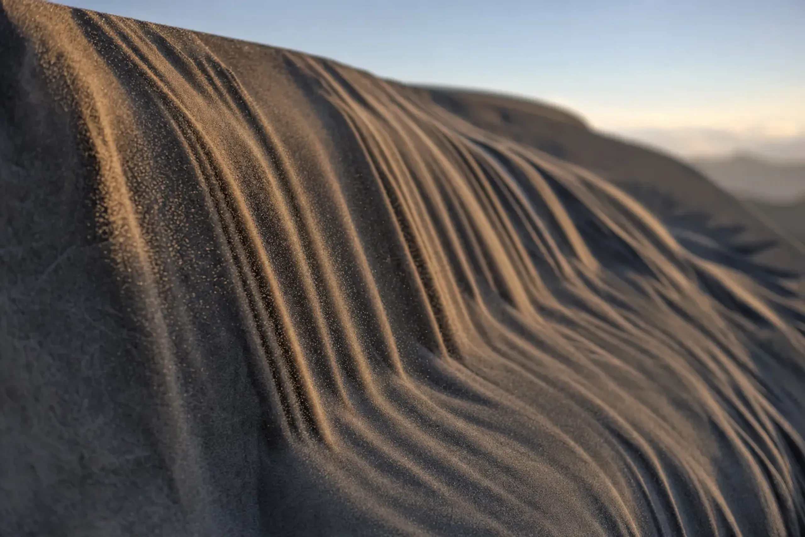 a sunadare sand curtain sliding down a steep dune slope, draping the incline in folded pleated texture