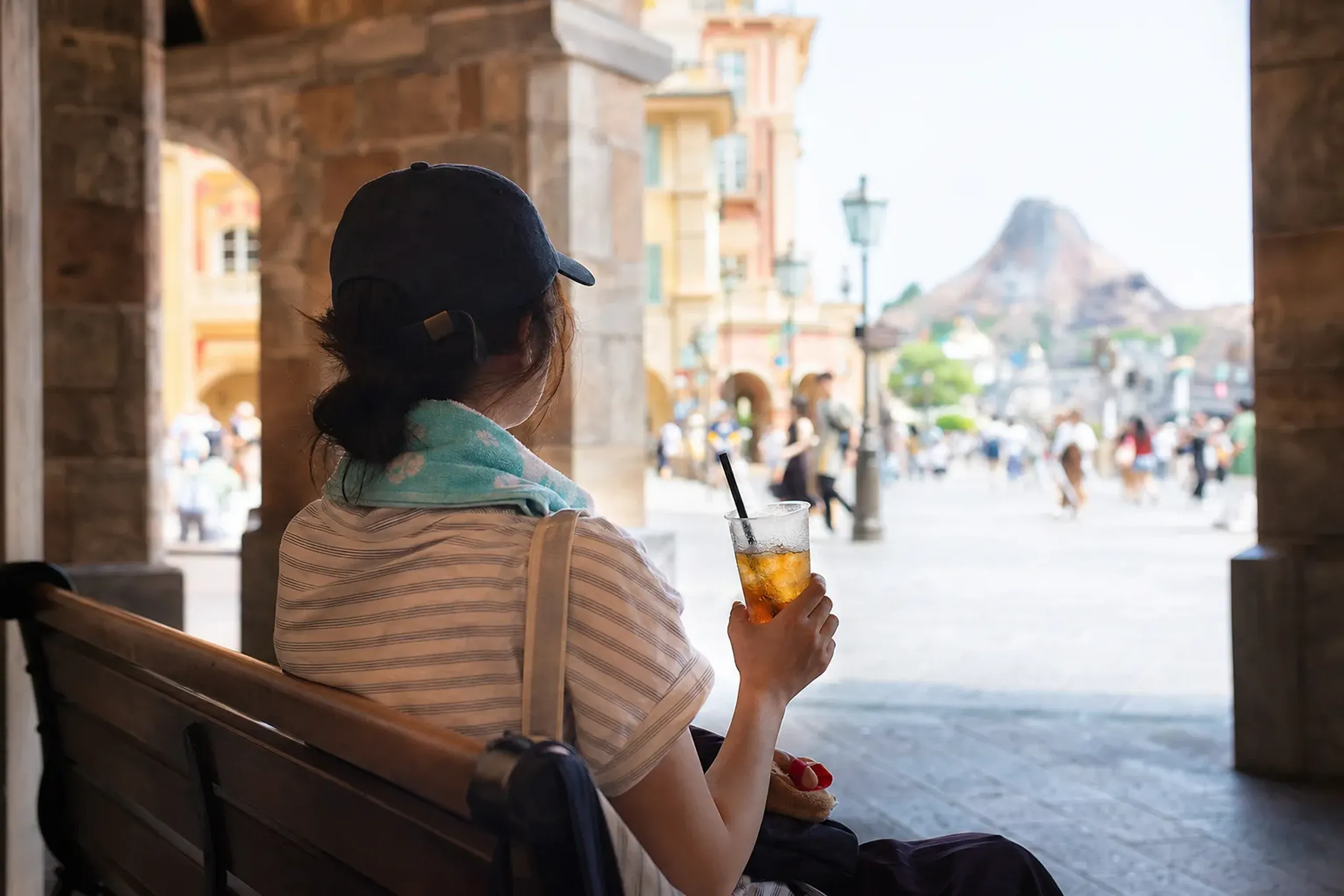 Guest seated indoors at Tokyo DisneySea taking a hydration break with a cold drink during summer heat
