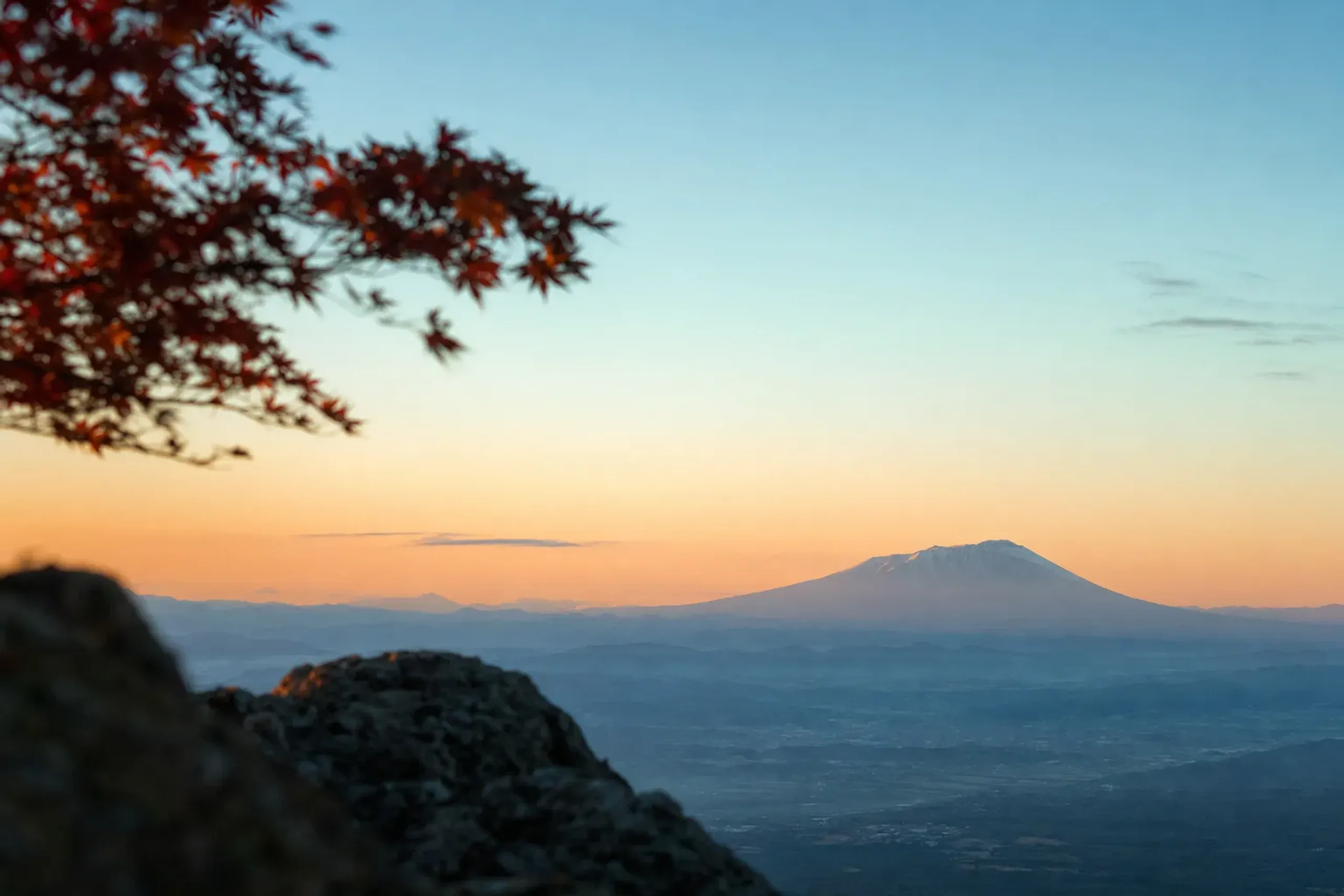 red foliage silhouetted against the profile of Mount Iwate as seen from Mitsuishi-yama