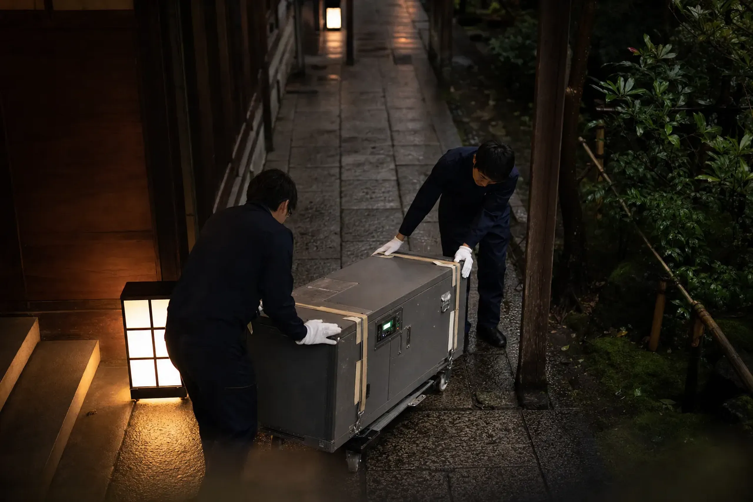 A climate-controlled art transport crate being carefully moved through a museum service entrance corridor