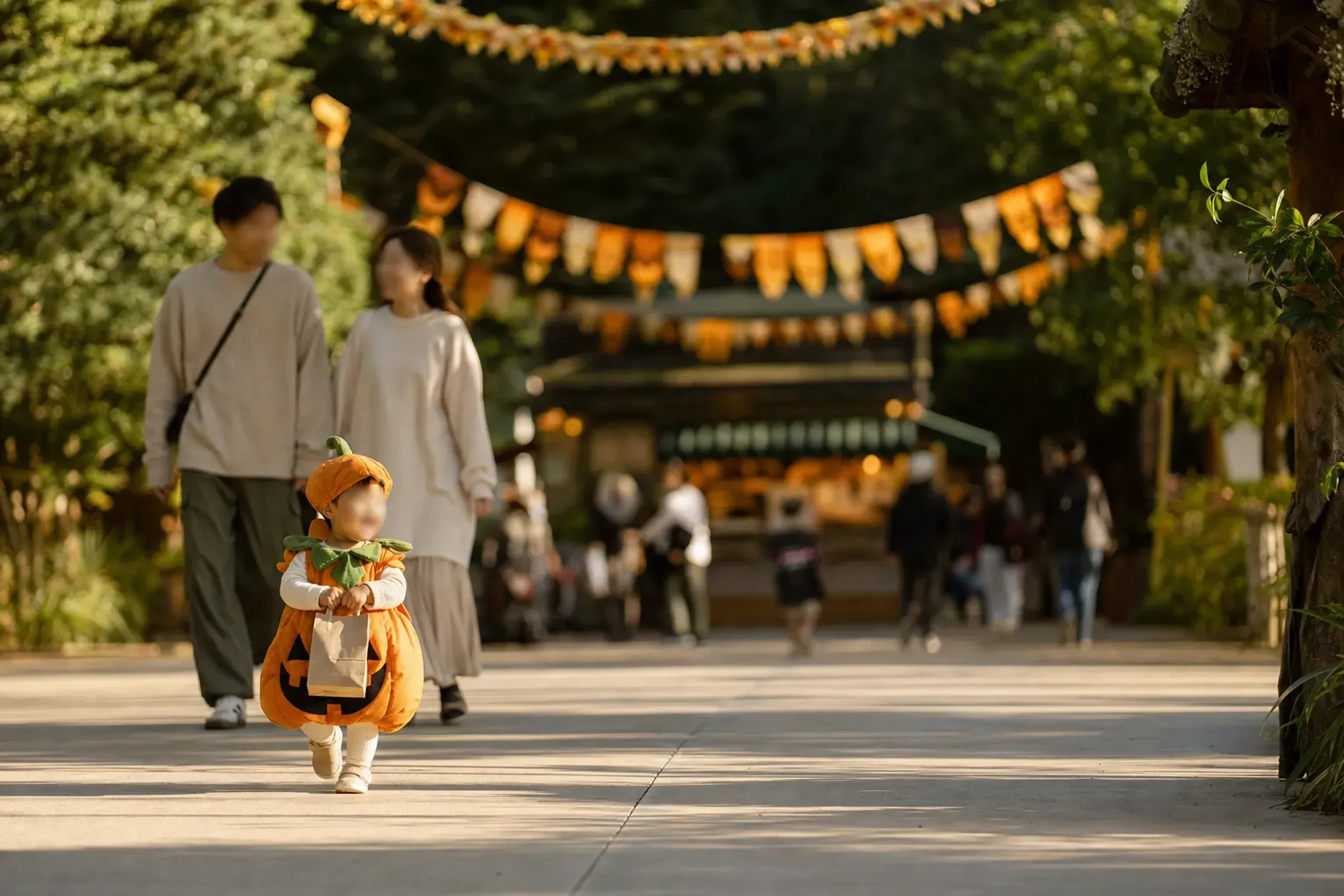 Children in simple costumes carrying treat bags during daytime Halloween programming at a theme park