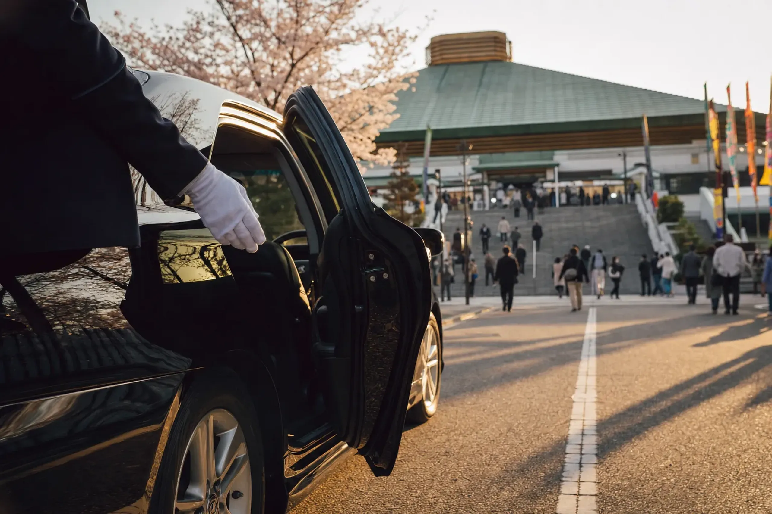 A black chauffeured sedan waiting at the entrance of the Ryogoku Kokugikan
