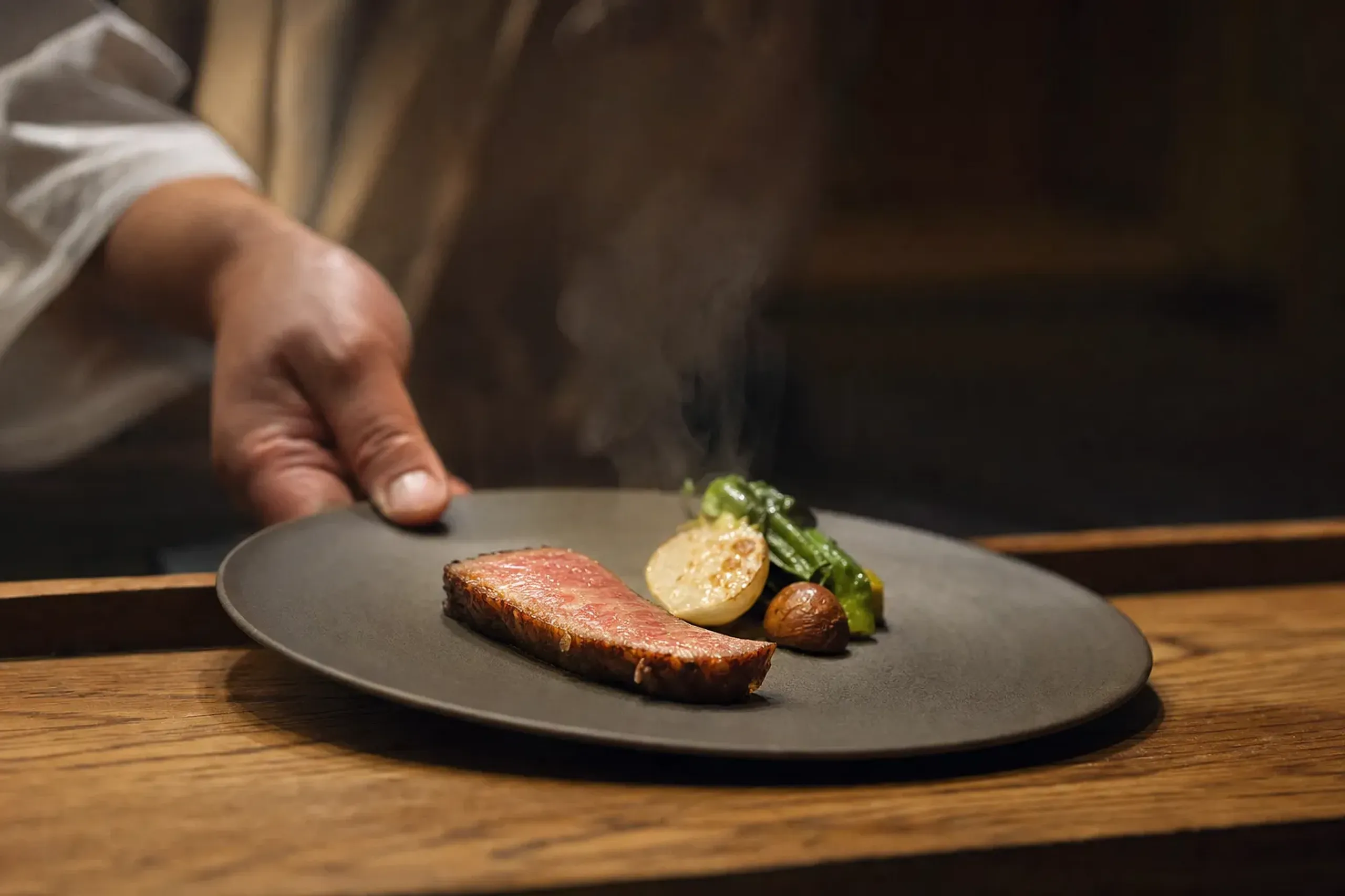 a winter chef's-table plate pairing a marbled wagyu cut with seasonal Japanese vegetables at their peak