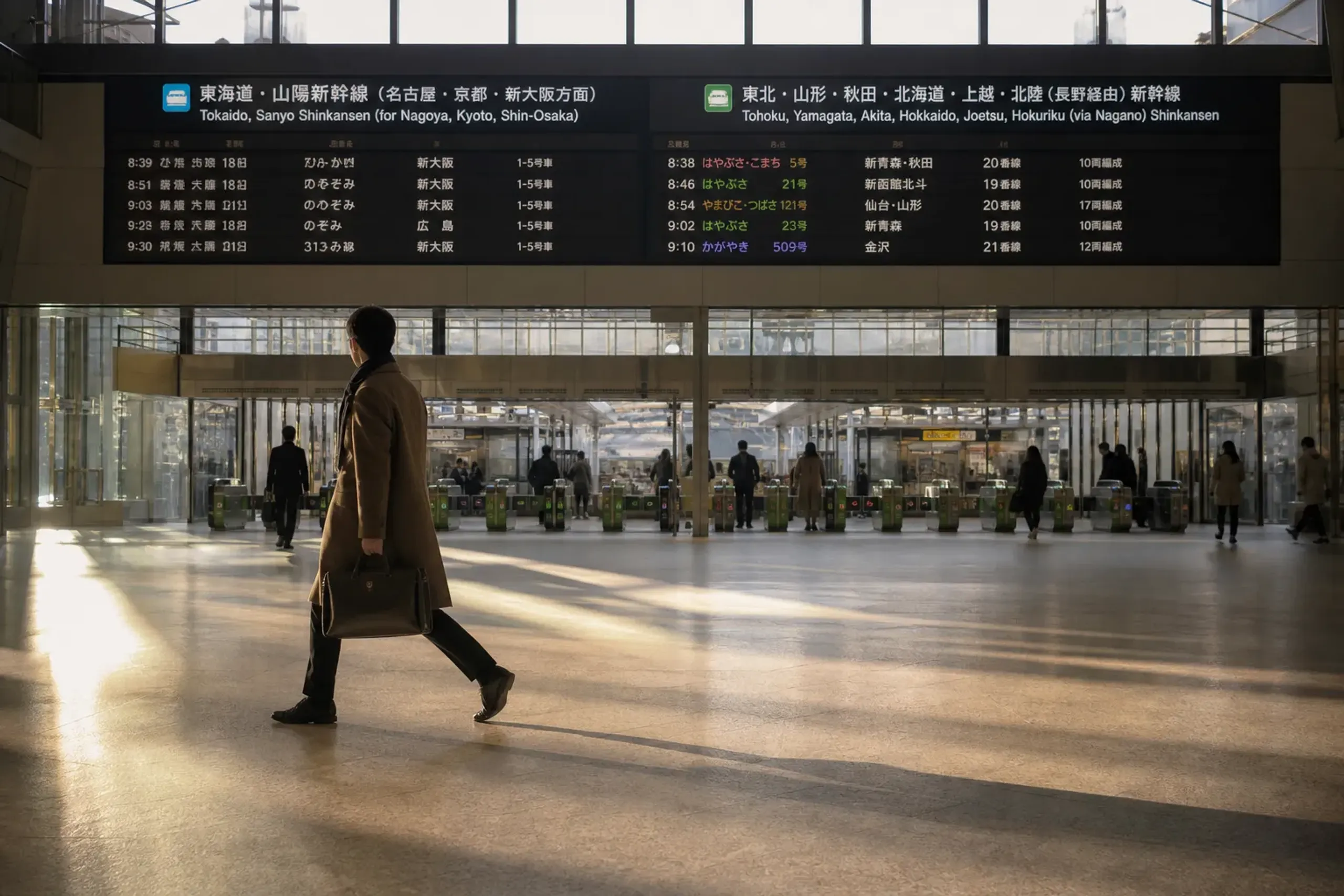 Traveler carrying a small overnight bag in Tokyo Station near Shinkansen signs