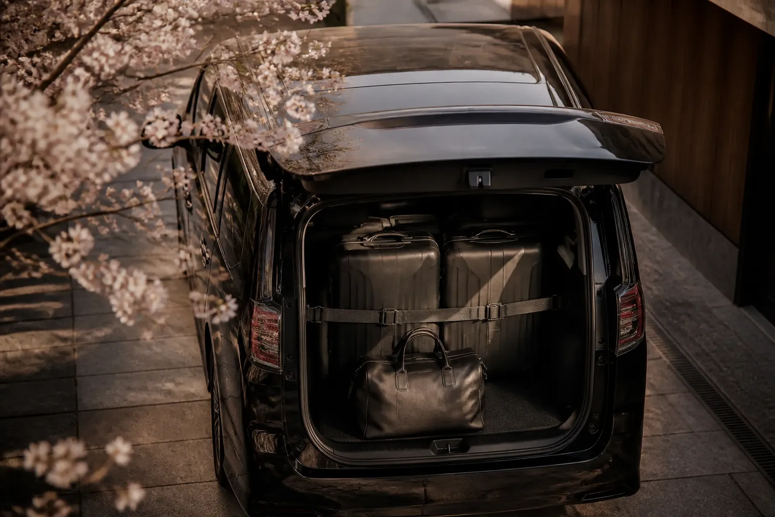Large suitcases secured in a luxury van with a small overnight bag nearby