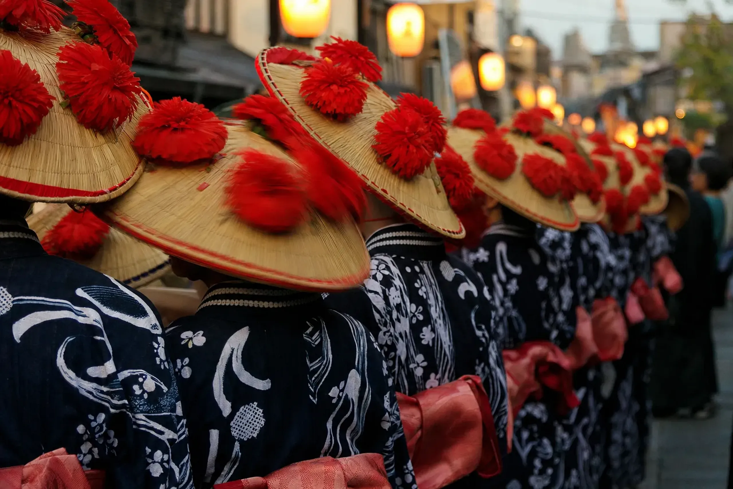 Street-level view from the crowded sidewalk along Yamagata's main street as red safflower hats pass an arm's length away during the evening parade