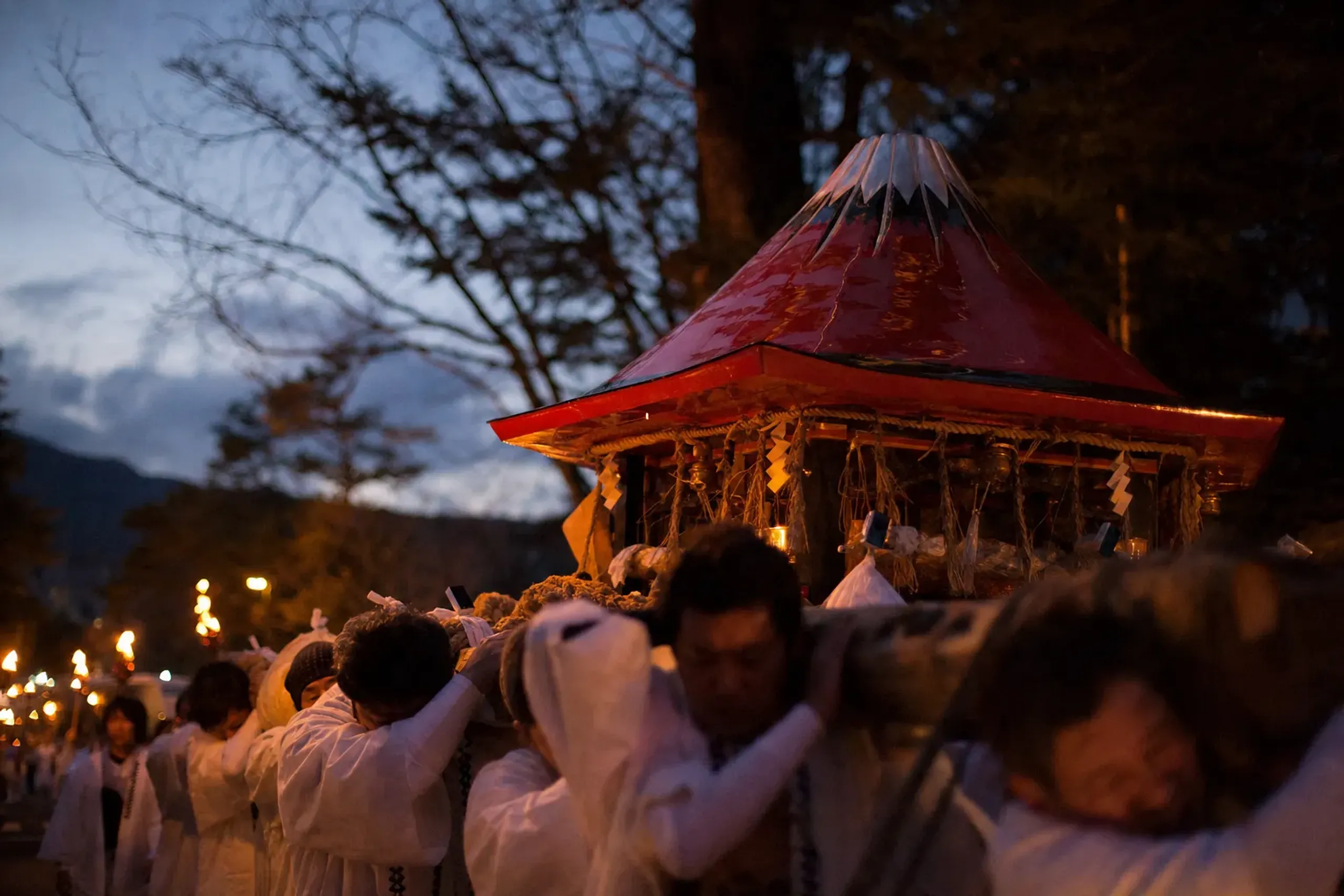 the vermilion Mount Fuji-shaped mikoshi portable shrine being carried through the streets of Fujiyoshida during the evening procession