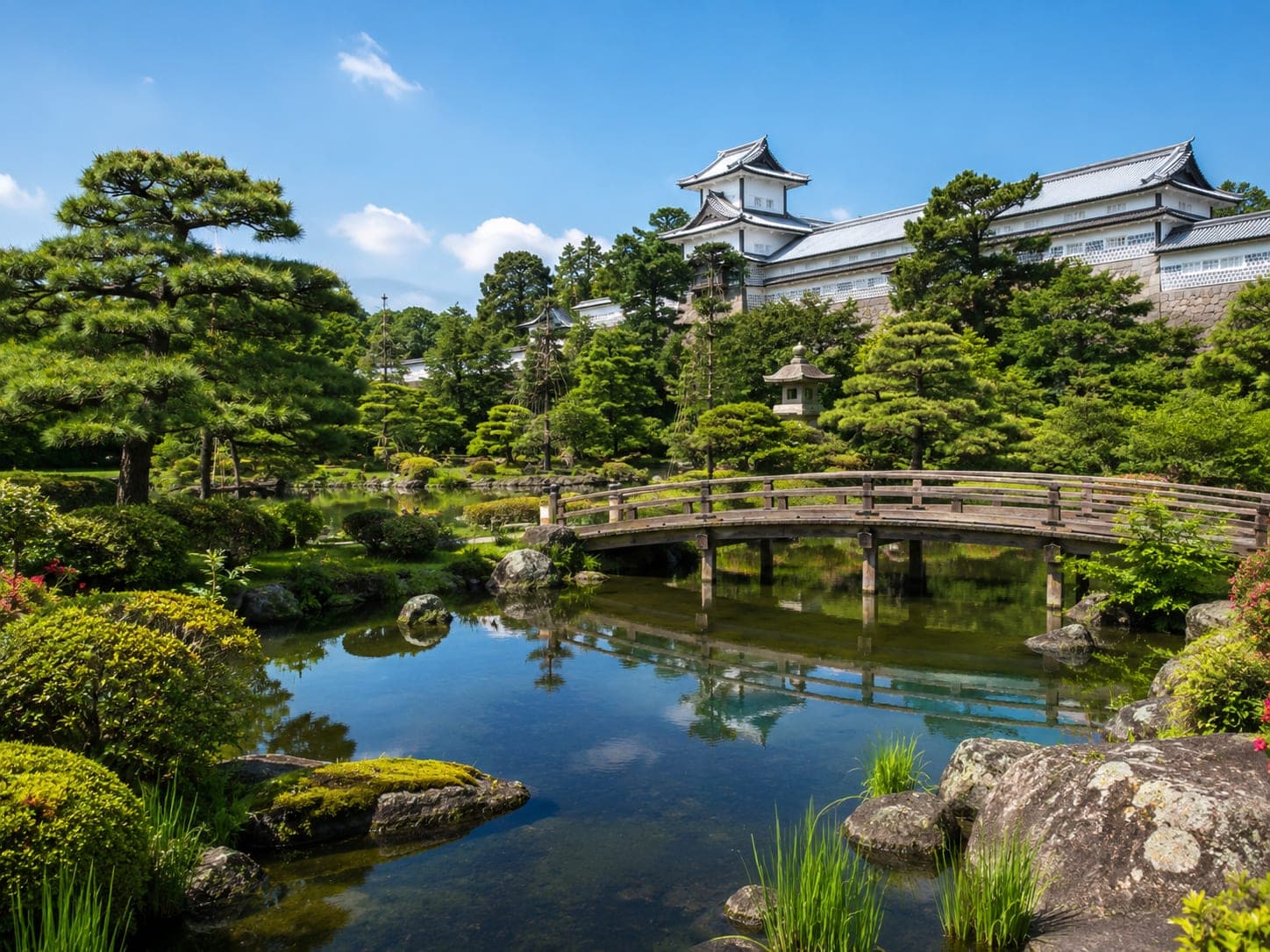 Garden with an arched bridge and pond below Kanazawa Castle