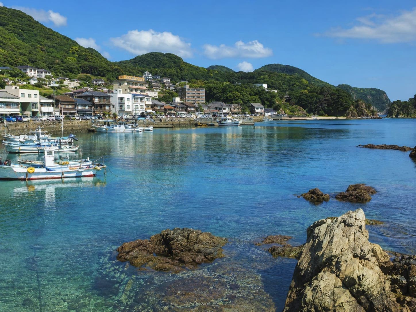 Fishing boats moored in a clear turquoise cove on the Izu coast at Shimoda