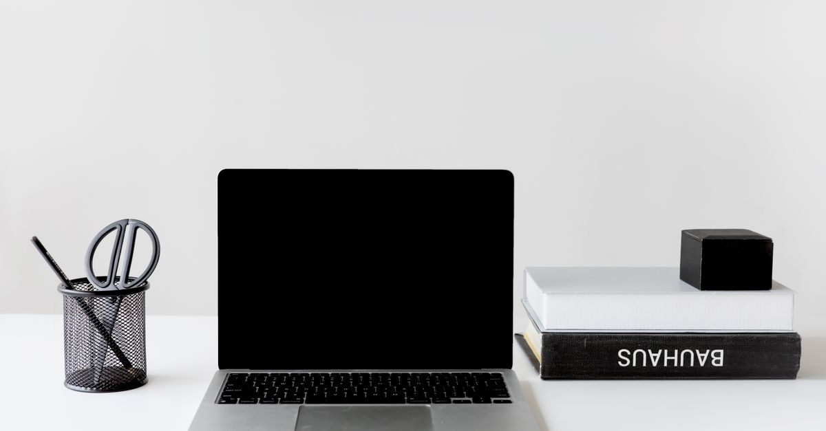 Laptop with a booking webpage, passport, and hotel key card on a desk