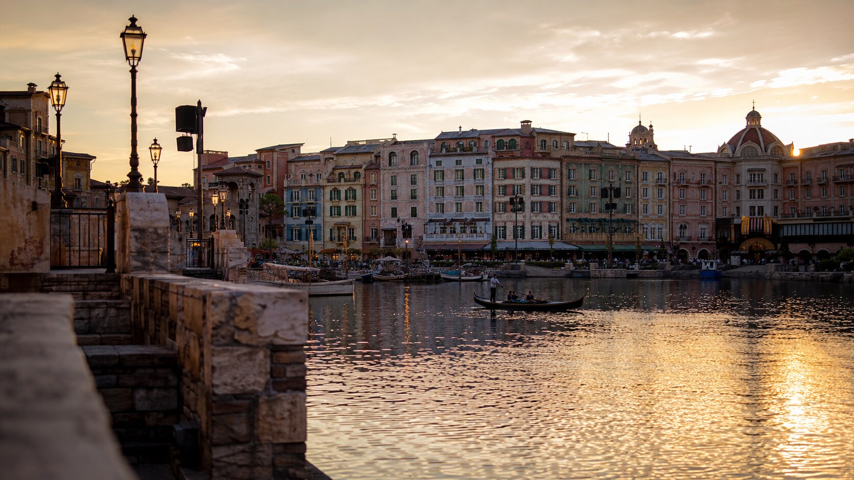 A serene, golden-hour view of the Mediterranean Harbor at Tokyo DisneySea, showcasing calm waters and elegant architecture bathed in warm sunlight.